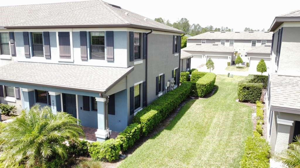 An aerial view shows a two-story blue townhouse with a side yard and hedges — 4609 BEXLEY VILLAGE DRIVE, LAND O LAKES, FL