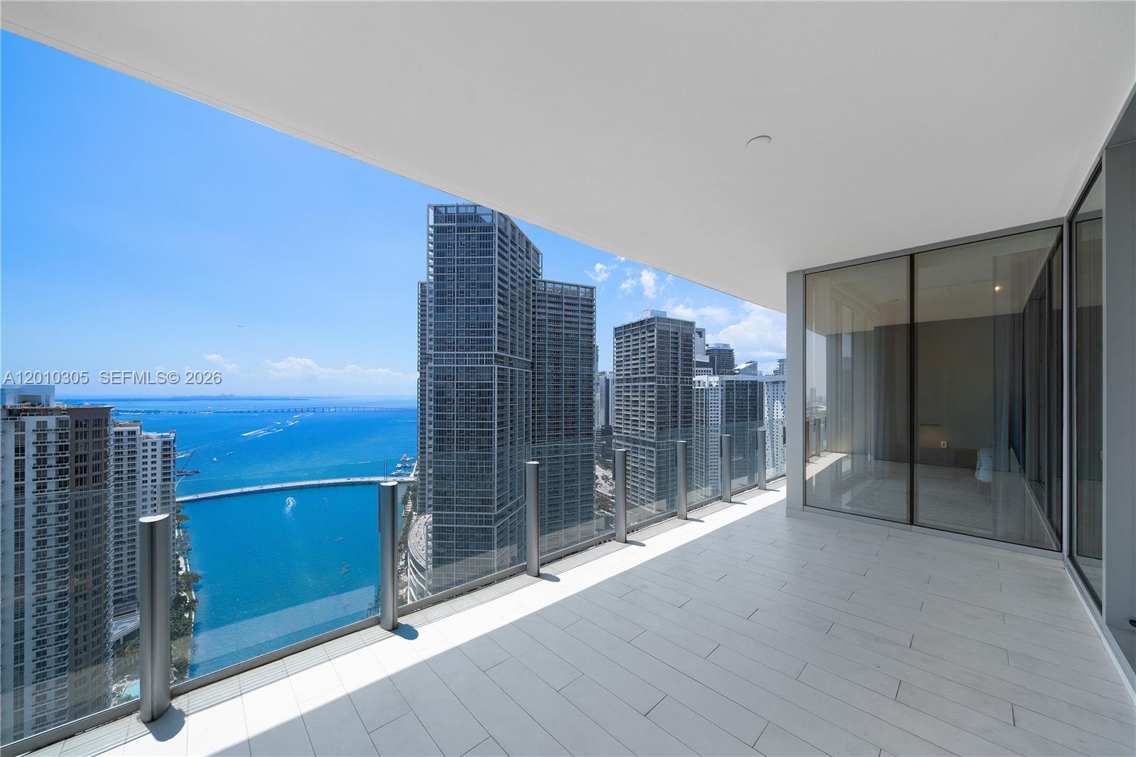 A modern balcony with glass railings overlooks a city skyline and the ocean — 300 Biscayne Blvd Way # 3503C, Miami FL 33131, MIAMI, FL