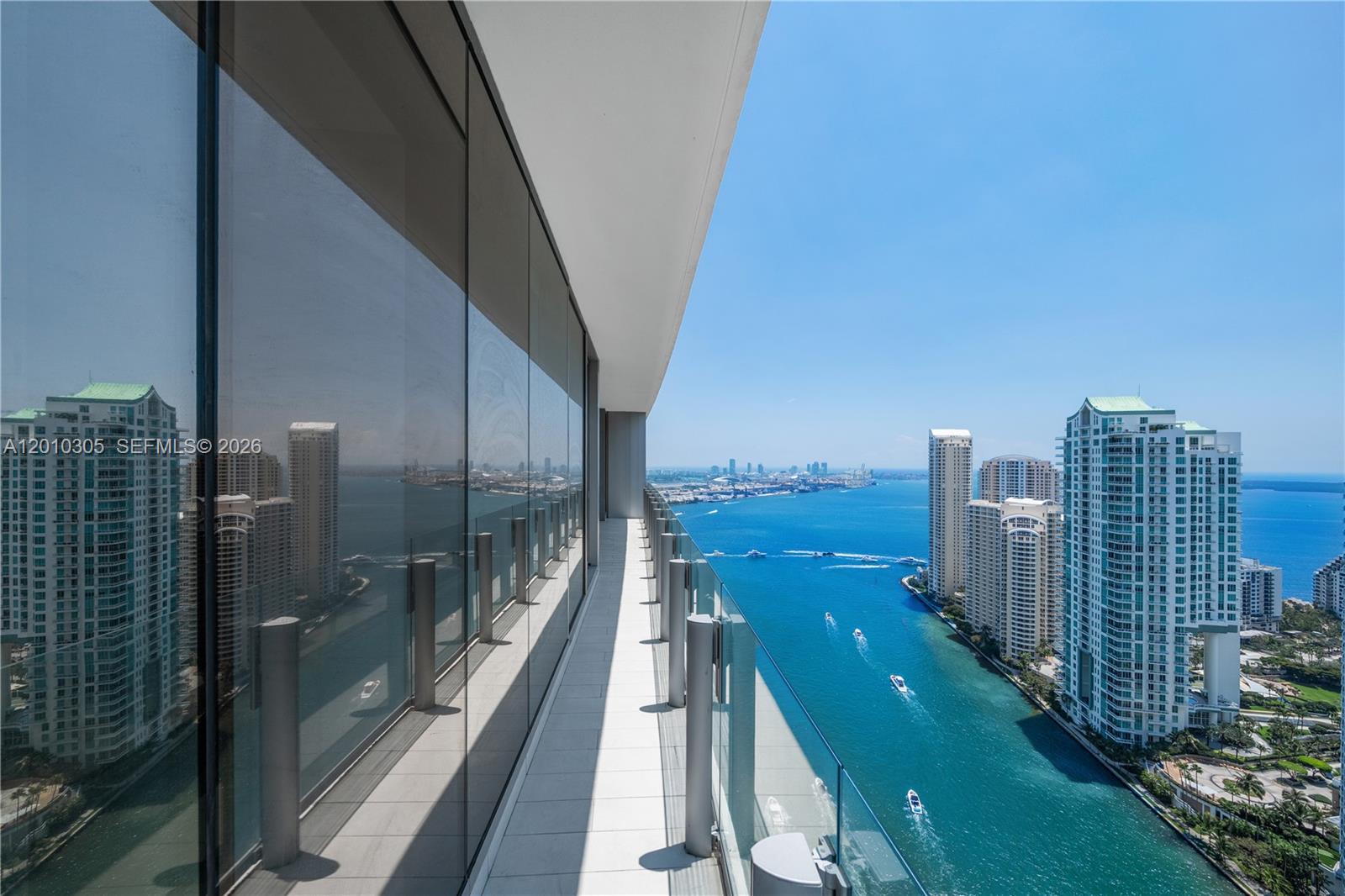 A high-rise balcony with a glass railing overlooks a bay with boats and city buildings — 300 Biscayne Blvd Way # 3503C, Miami FL 33131, MIAMI, FL