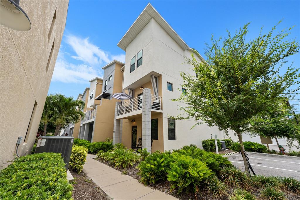 A multi-story townhouse exterior features a balcony, a concrete walkway, and surrounding landscaping — 2522 12TH TERRACE N, ST PETERSBURG, FL
