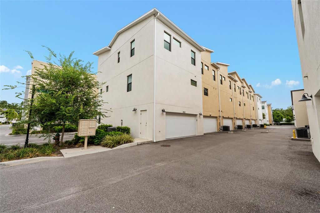 A row of multi-story townhomes features white and tan stucco exteriors with attached garages — 2522 12TH TERRACE N, ST PETERSBURG, FL
