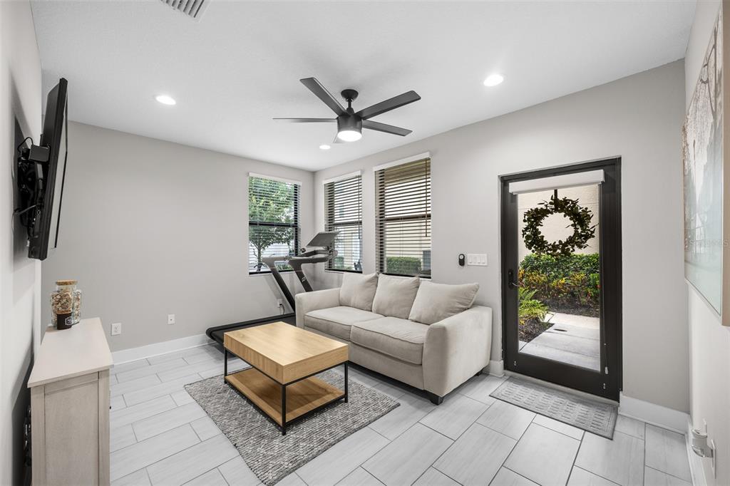 A living room features a sofa, coffee table, treadmill, and a glass door to outside — 2522 12TH TERRACE N, ST PETERSBURG, FL
