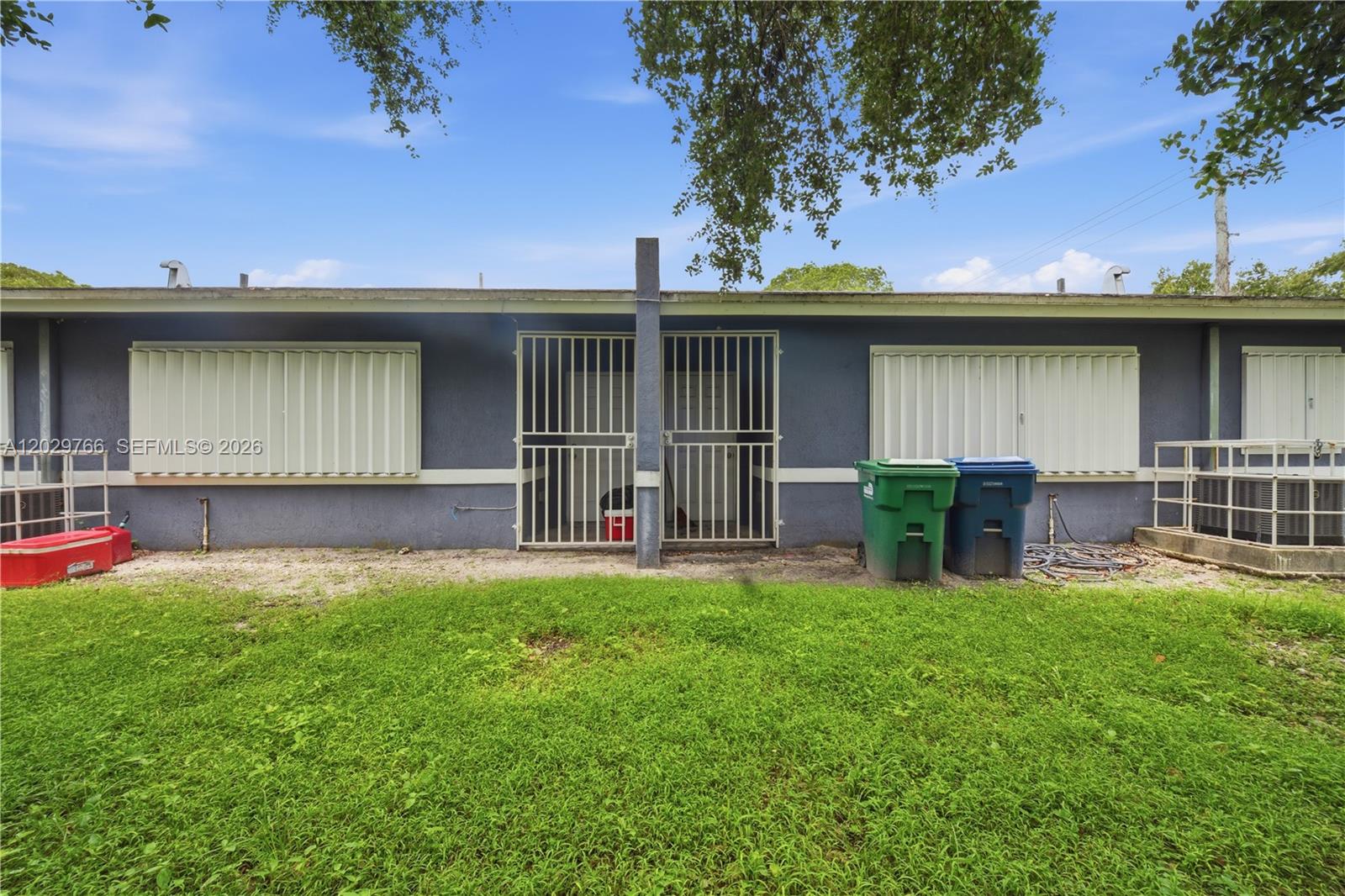 The exterior of a blue building features metal security shutters and two gated entryways — 2249/2251 NW 66th St, Miami FL 33147, MIAMI, FL