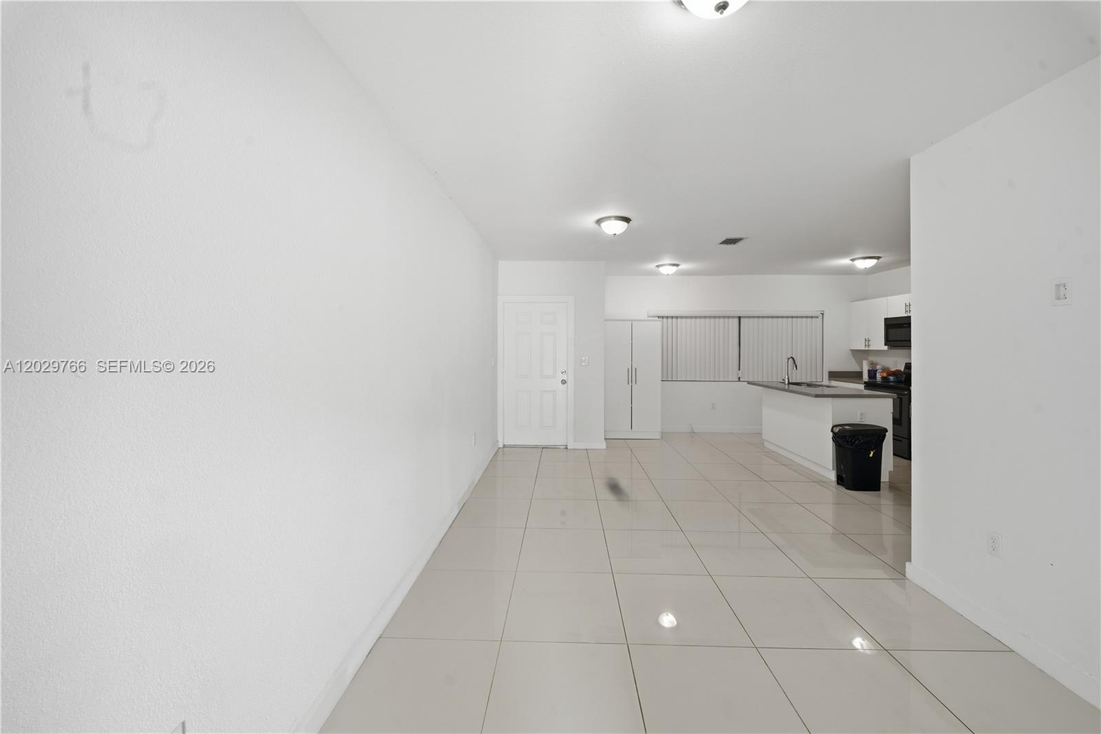 An open-concept living area features white walls, large light-colored floor tiles, and a kitchen — 2249/2251 NW 66th St, Miami FL 33147, MIAMI, FL