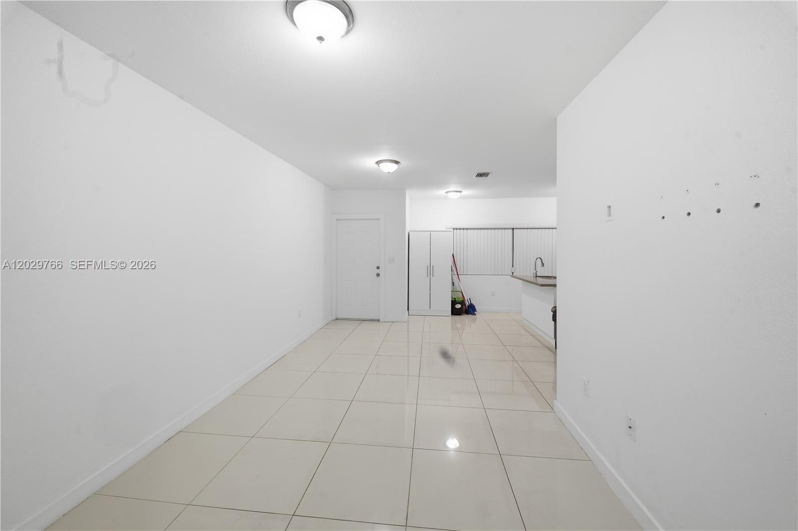 A bright, open-concept room features white walls, light-colored tile flooring, and a kitchen area — 2249/2251 NW 66th St, Miami FL 33147, MIAMI, FL