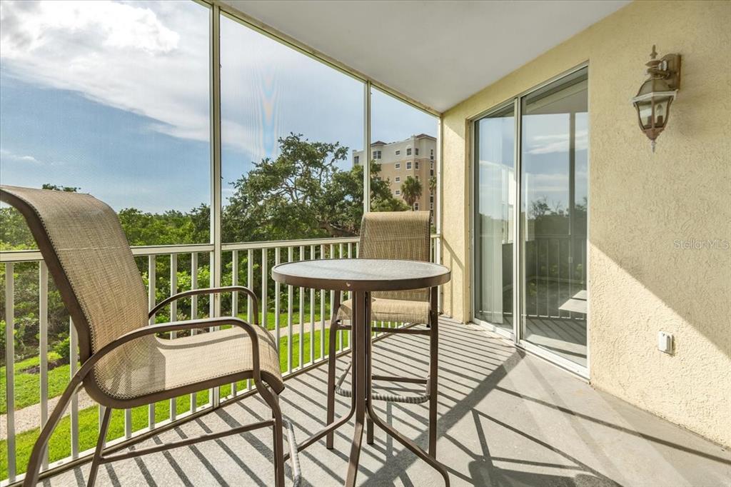 A screened-in balcony features a small bistro table with two chairs and sliding glass doors — 2625 TERRA CEIA BAY BOULEVARD UNIT 103, PALMETTO, FL