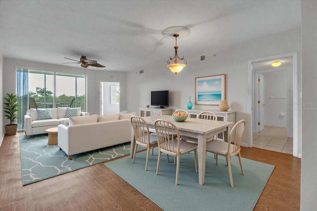 A living and dining room with white furniture, light wood floors, and a balcony view — 2625 TERRA CEIA BAY BOULEVARD UNIT 103, PALMETTO, FL