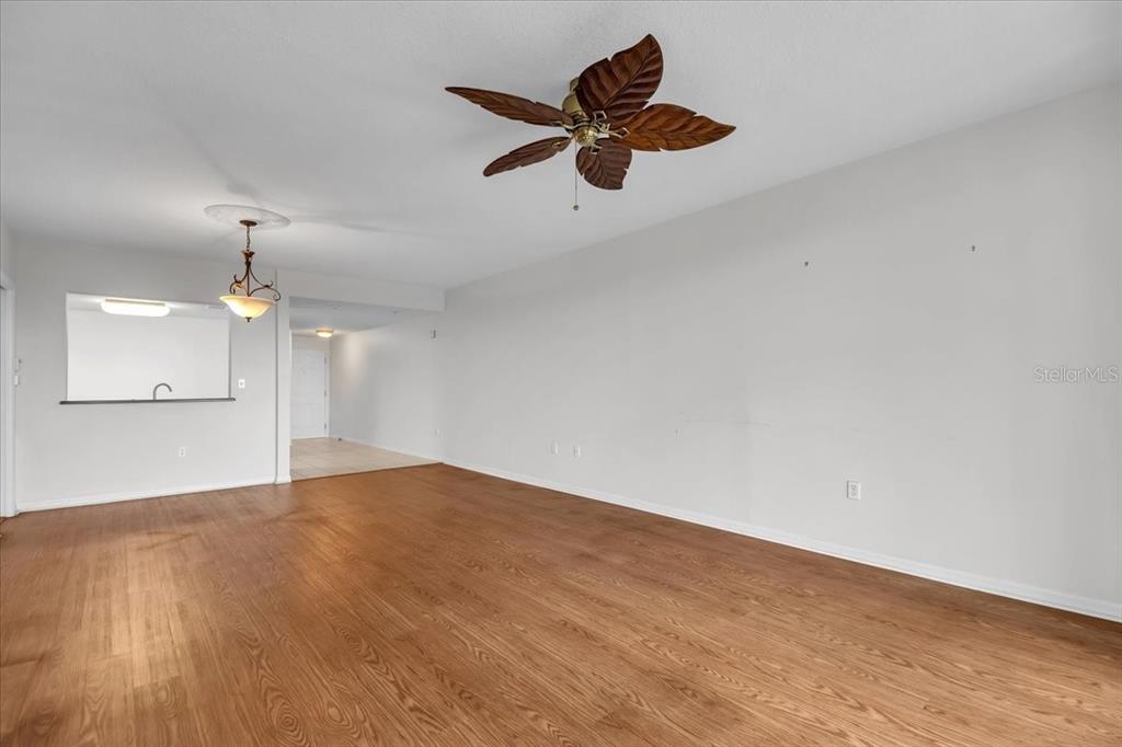 An empty living room features wood-look flooring, a leaf-shaped ceiling fan, and a pass-through window — 2625 TERRA CEIA BAY BOULEVARD UNIT 103, PALMETTO, FL