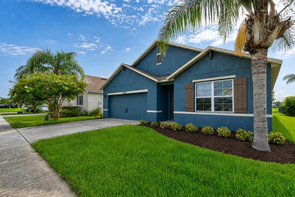 A blue single-story house with a two-car garage, brown shutters, and a palm tree — 2989 GIBRALTAR BOULEVARD, NEW SMYRNA BEACH, FL