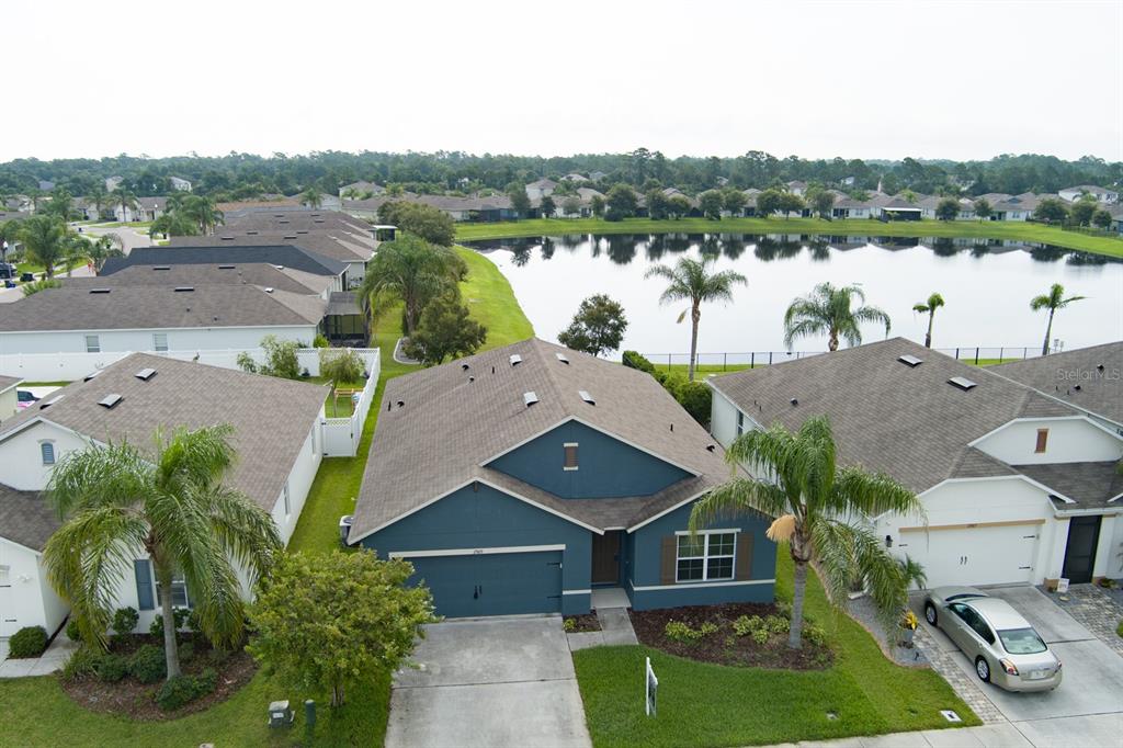 An aerial view shows a blue suburban house with a brown roof near a lake — 2989 GIBRALTAR BOULEVARD, NEW SMYRNA BEACH, FL