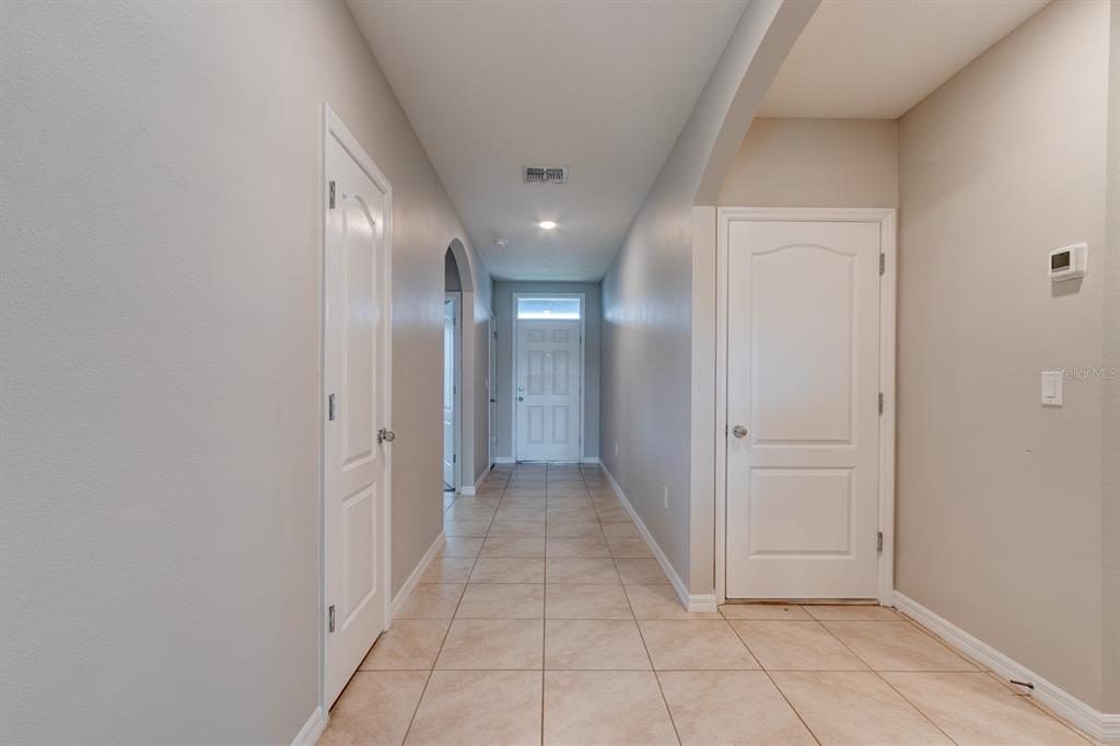 A hallway with light-colored tile flooring, beige walls, and white interior doors — 2989 GIBRALTAR BOULEVARD, NEW SMYRNA BEACH, FL