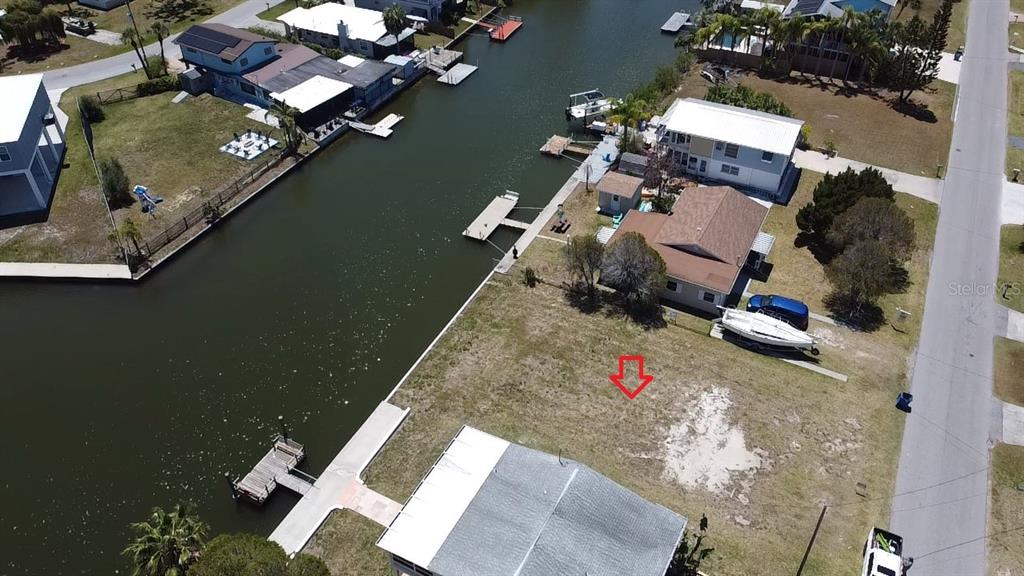 An aerial view shows a vacant waterfront lot situated between two houses along a canal — 4018 EAGLE NEST DRIVE, HERNANDO BEACH, FL