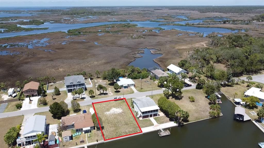 An aerial view shows a vacant waterfront lot outlined in red between two houses — 4018 EAGLE NEST DRIVE, HERNANDO BEACH, FL