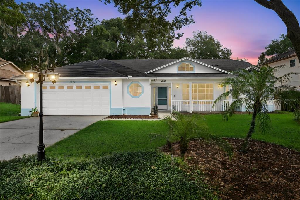 A single-story house with a white exterior, blue trim, a two-car garage, and a front porch — 1748 IMPERIAL PALM DRIVE, APOPKA, FL