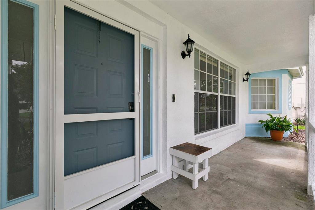 A covered front porch features a blue storm door, a white bench, and exterior lighting — 1748 IMPERIAL PALM DRIVE, APOPKA, FL