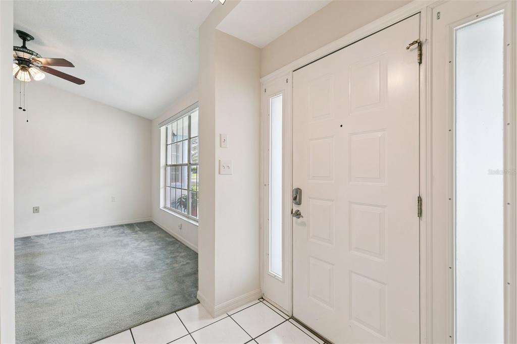 An entryway with white tiled floors leads to a carpeted room with a ceiling fan — 1748 IMPERIAL PALM DRIVE, APOPKA, FL