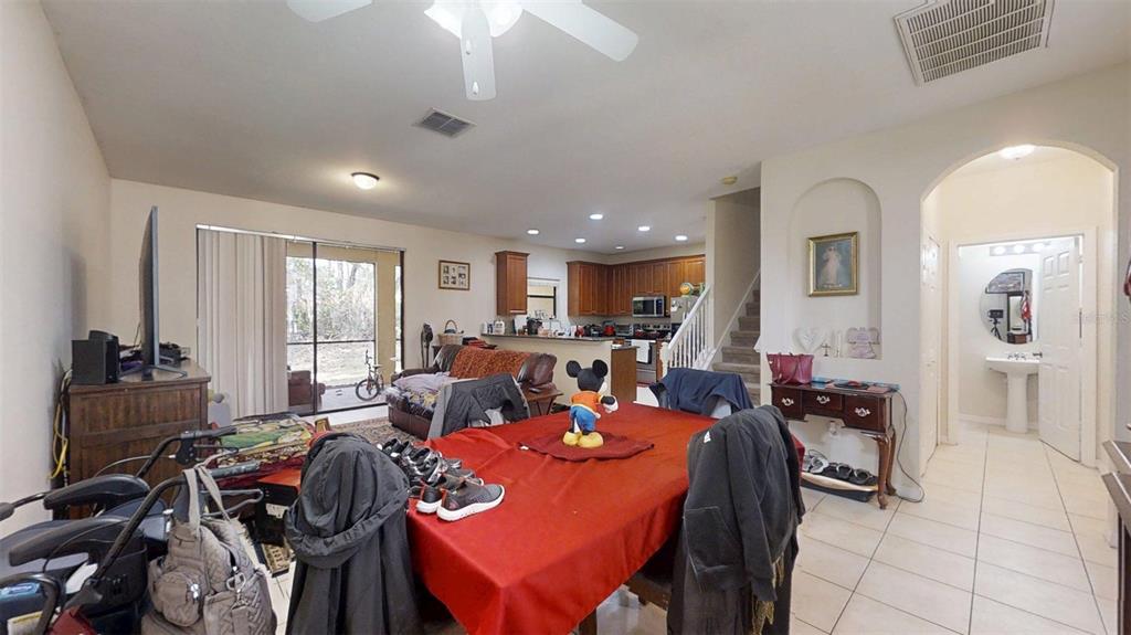 A dining area with a red tablecloth leads into an open kitchen and living space — 1370 PACIFIC ROAD, KISSIMMEE, FL