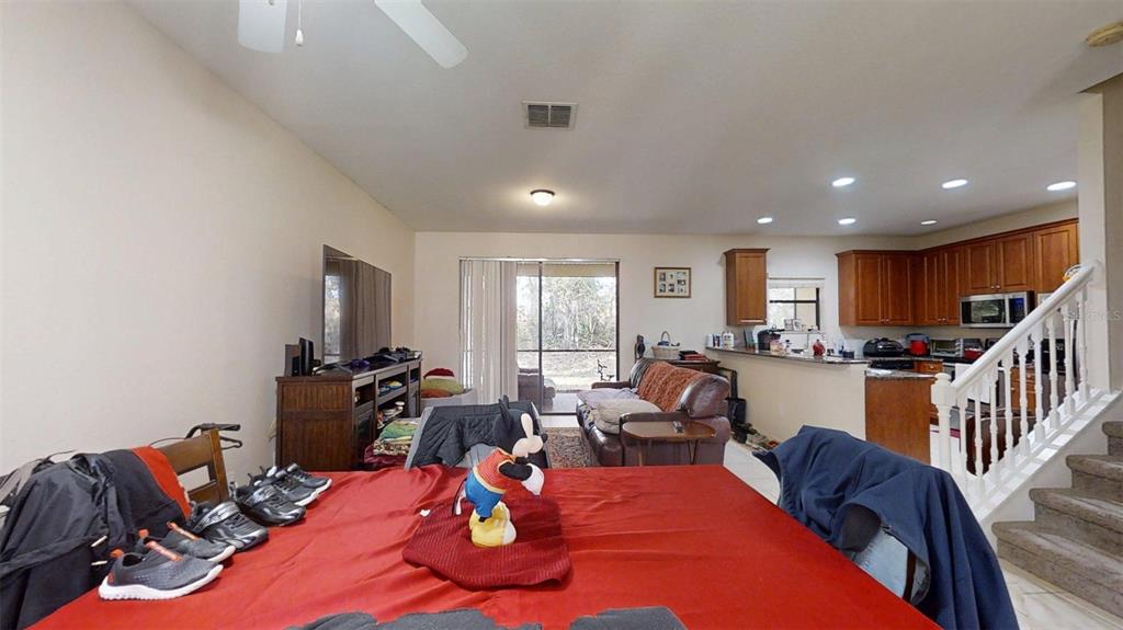 A dining area with a red tablecloth leads into a living room and open kitchen — 1370 PACIFIC ROAD, KISSIMMEE, FL