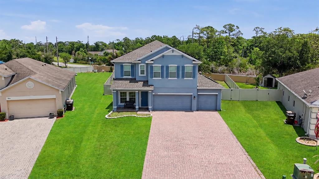 An aerial view shows a two-story blue house with a brick driveway and green lawn — 3830 SPIRITED CIRCLE, ST CLOUD, FL