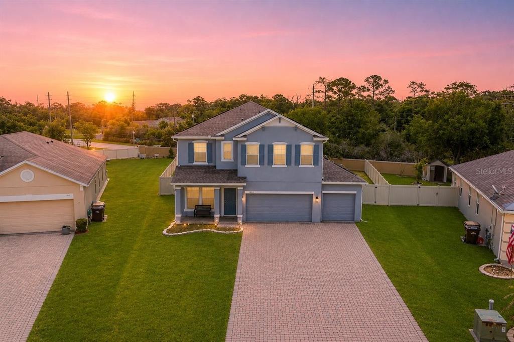 An aerial view of a two-story blue house with a paved driveway at sunset — 3830 SPIRITED CIRCLE, ST CLOUD, FL