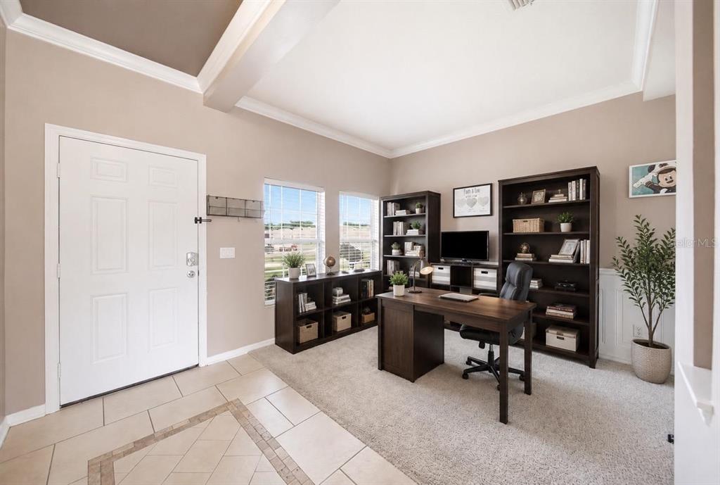 A home office with dark wood furniture, beige walls, and carpeted flooring near an entryway — 3830 SPIRITED CIRCLE, ST CLOUD, FL