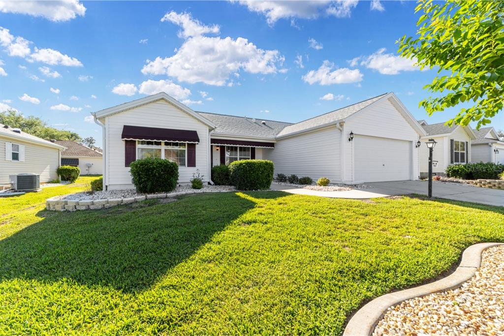 A single-story white house with a two-car garage and a manicured front lawn — 17637 SE 80TH ALTAMAHA COURT, THE VILLAGES, FL