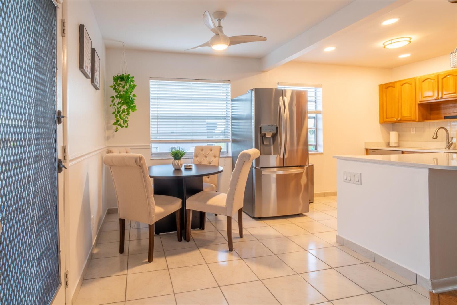 A dining area with a round table and chairs sits next to a stainless steel refrigerator — 313 Burgundy G, Delray Beach FL 33484, DELRAY BEACH, FL