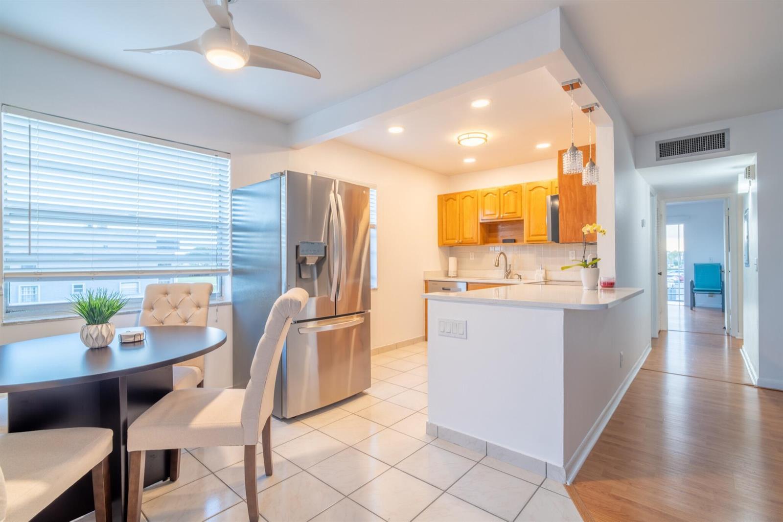 A kitchen with light wood cabinets and stainless steel appliances opens to a dining area — 313 Burgundy G, Delray Beach FL 33484, DELRAY BEACH, FL