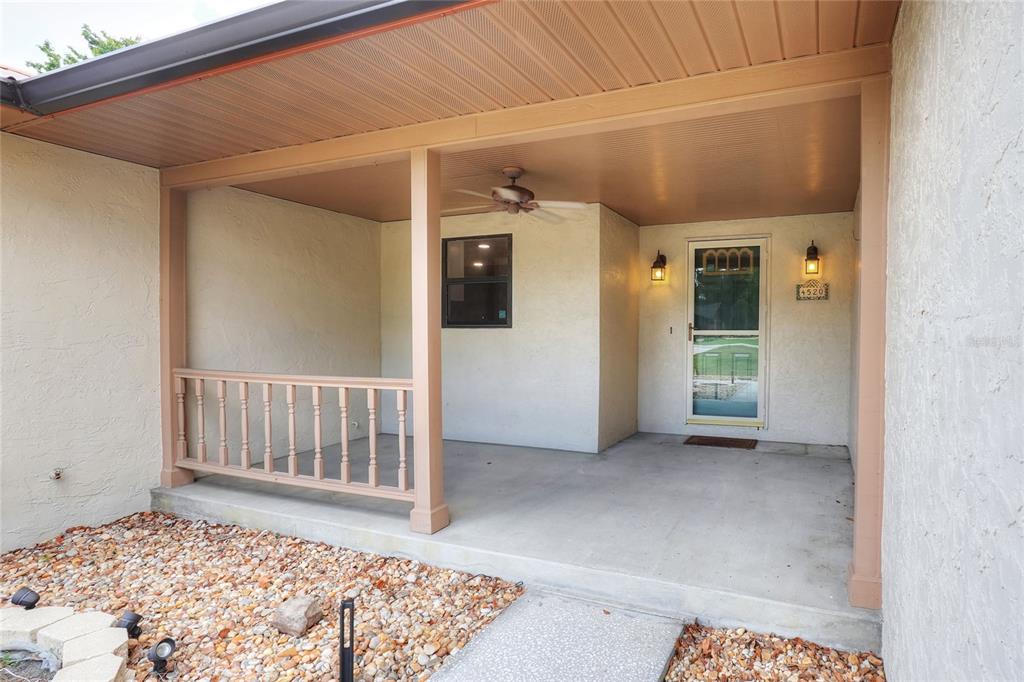 A covered front porch with a concrete floor, wooden railing, and a ceiling fan — 4520 LOG CABIN DRIVE, LAKELAND, FL