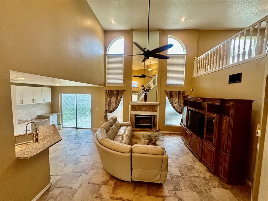 A living room with a fireplace, tile floors, and a vaulted ceiling with a ceiling fan — 4519 ASHFORD DRIVE, WINTER HAVEN, FL