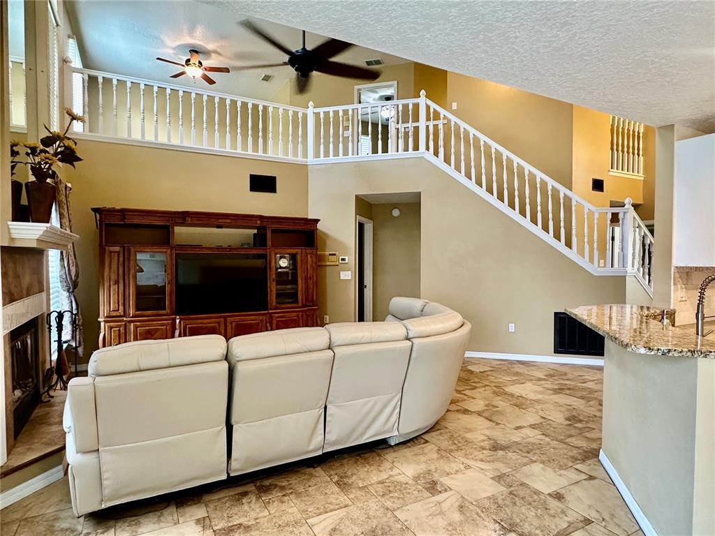 A living room features a large sectional sofa, a wooden entertainment center, and a staircase — 4519 ASHFORD DRIVE, WINTER HAVEN, FL
