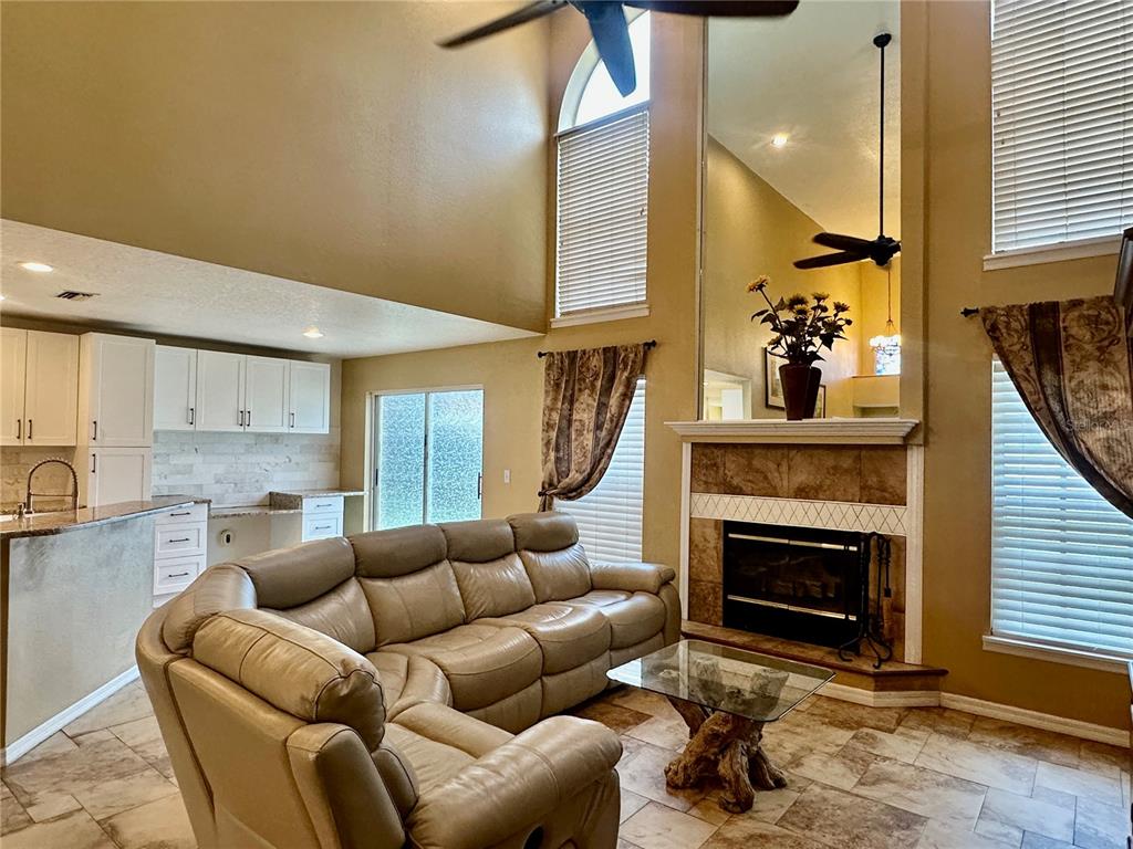 A living room with a tan sectional sofa, tiled floors, and a fireplace with a mirror — 4519 ASHFORD DRIVE, WINTER HAVEN, FL