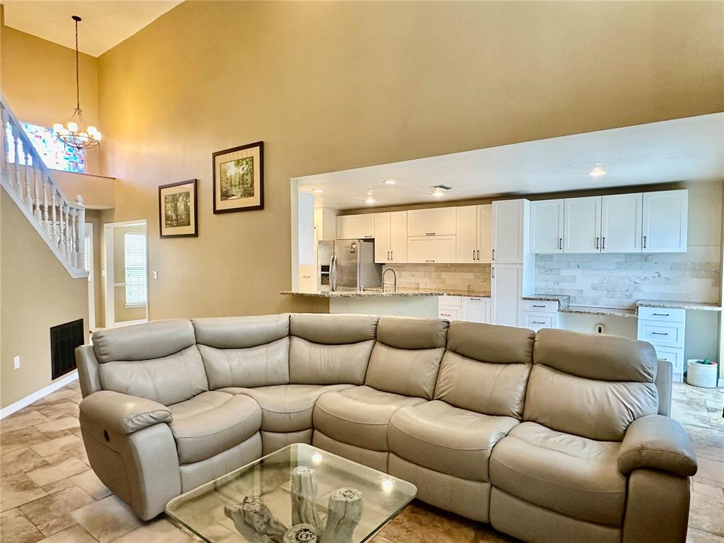 A living room with a large sectional sofa faces an open kitchen with white cabinets — 4519 ASHFORD DRIVE, WINTER HAVEN, FL