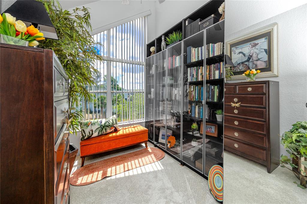 A sunlit room features a tall glass-front bookcase, an orange bench, and a large window — 14761 SEMINOLE TRAIL, SEMINOLE, FL