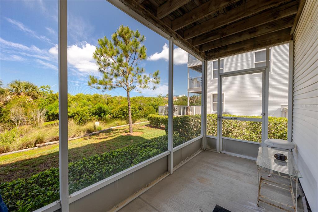A screened-in porch features a concrete floor, a glass-topped table, and views of landscaping — 14761 SEMINOLE TRAIL, SEMINOLE, FL