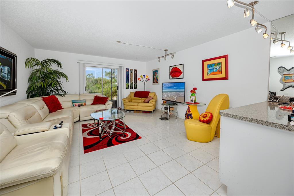A living room with white tile floors, a large sectional sofa, and colorful wall art — 14761 SEMINOLE TRAIL, SEMINOLE, FL