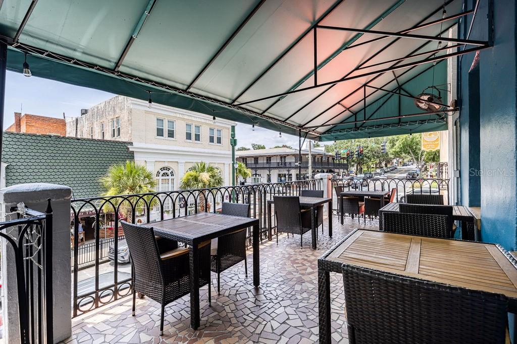 An outdoor balcony features a covered seating area with tables, chairs, and a tiled floor — 440 N DONNELLY STREET, MOUNT DORA, FL