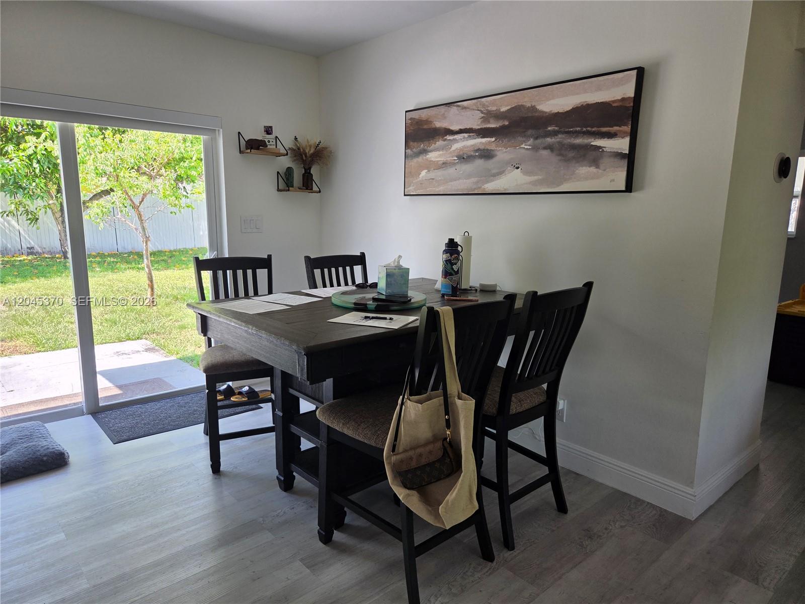 A dining area features a dark wood table, four chairs, and a sliding glass door — 140 NW 18th St, Pompano Beach FL 33060, POMPANO BEACH, FL