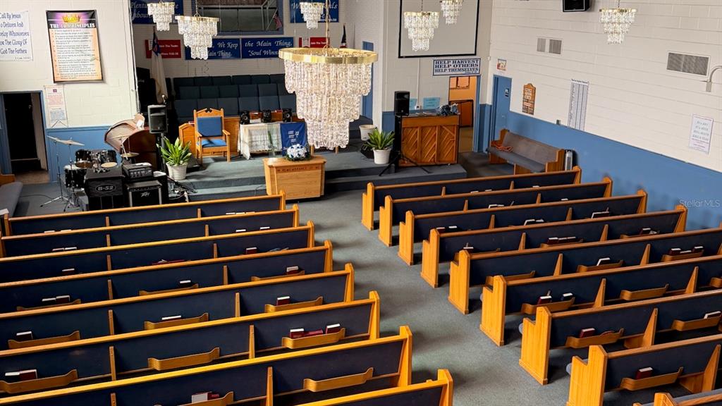 An interior view of a church sanctuary featuring rows of wooden pews and crystal chandeliers — 514 S PARRAMORE AVENUE, ORLANDO, FL