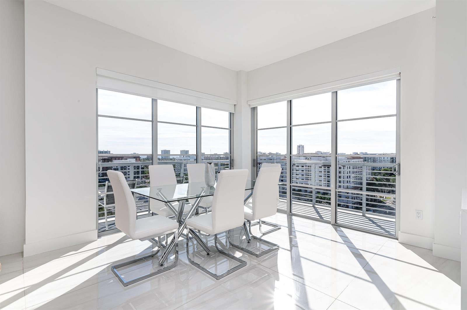 A dining room with a glass table, white chairs, tile floors, and floor-to-ceiling windows — 155 E Boca Raton Road # 1103, Boca Raton FL 33432, BOCA RATON, FL