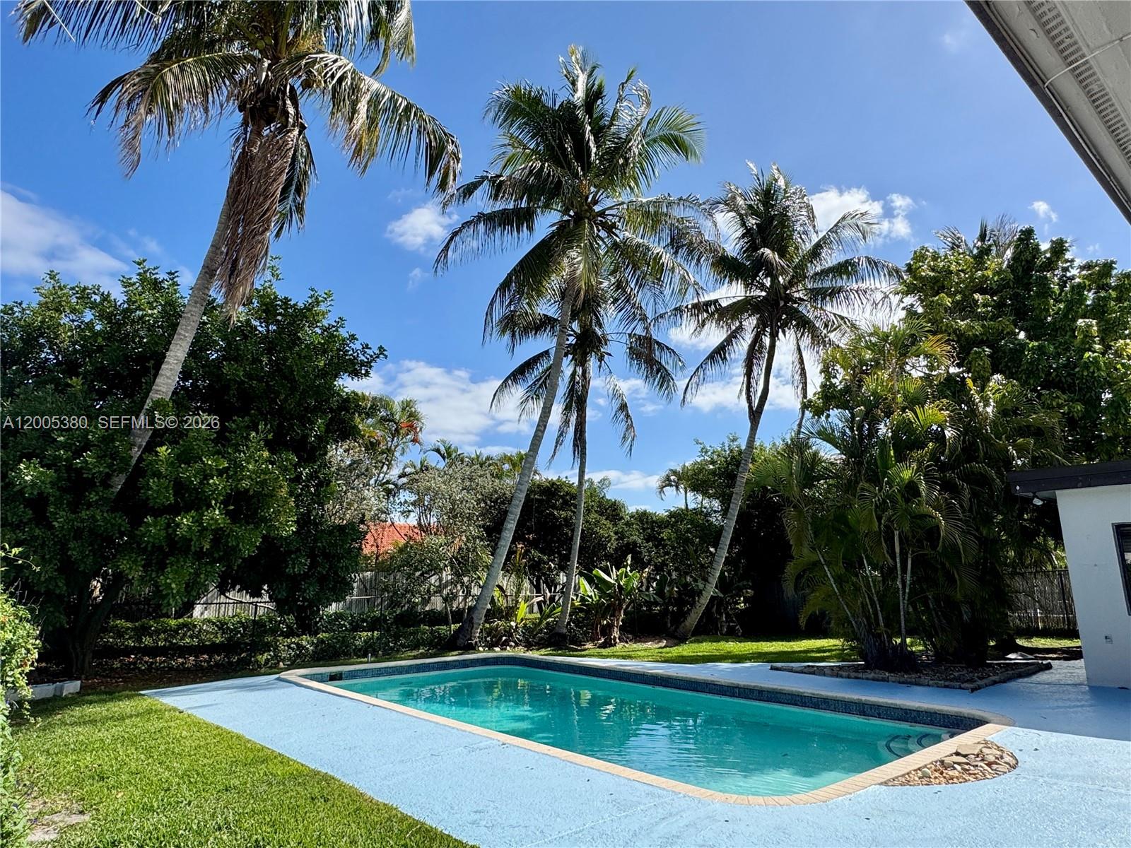 A rectangular swimming pool sits in a backyard surrounded by palm trees and green lawn — 13425 NW 10th St, Sunrise FL 33323, SUNRISE, FL