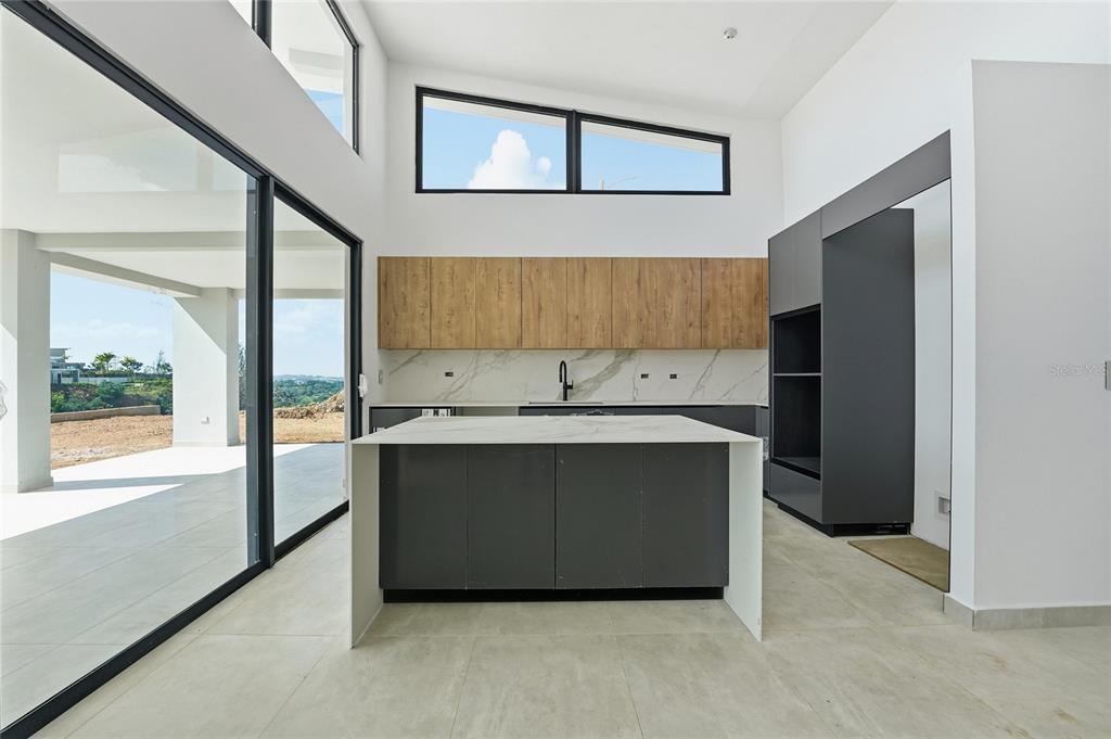 A modern kitchen features a central island, wood-toned upper cabinets, and large floor-to-ceiling windows — Monte azul MONTEAZUL, GUAYNABO, PR