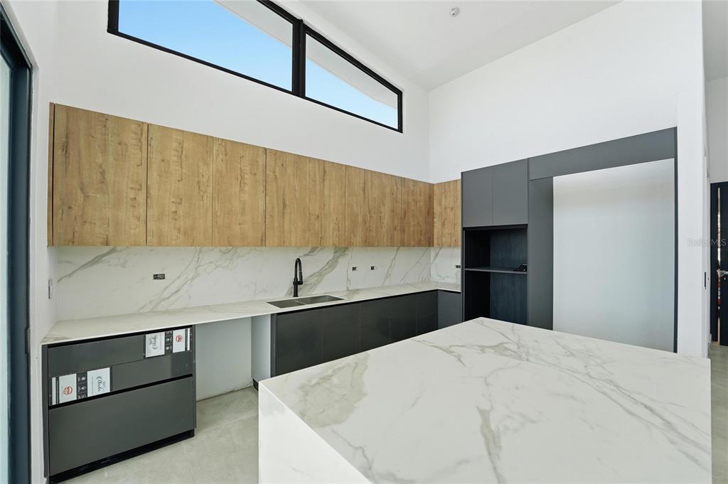 A modern kitchen features wood-tone upper cabinets, dark lower cabinets, and white marble countertops — Monte azul MONTEAZUL, GUAYNABO, PR