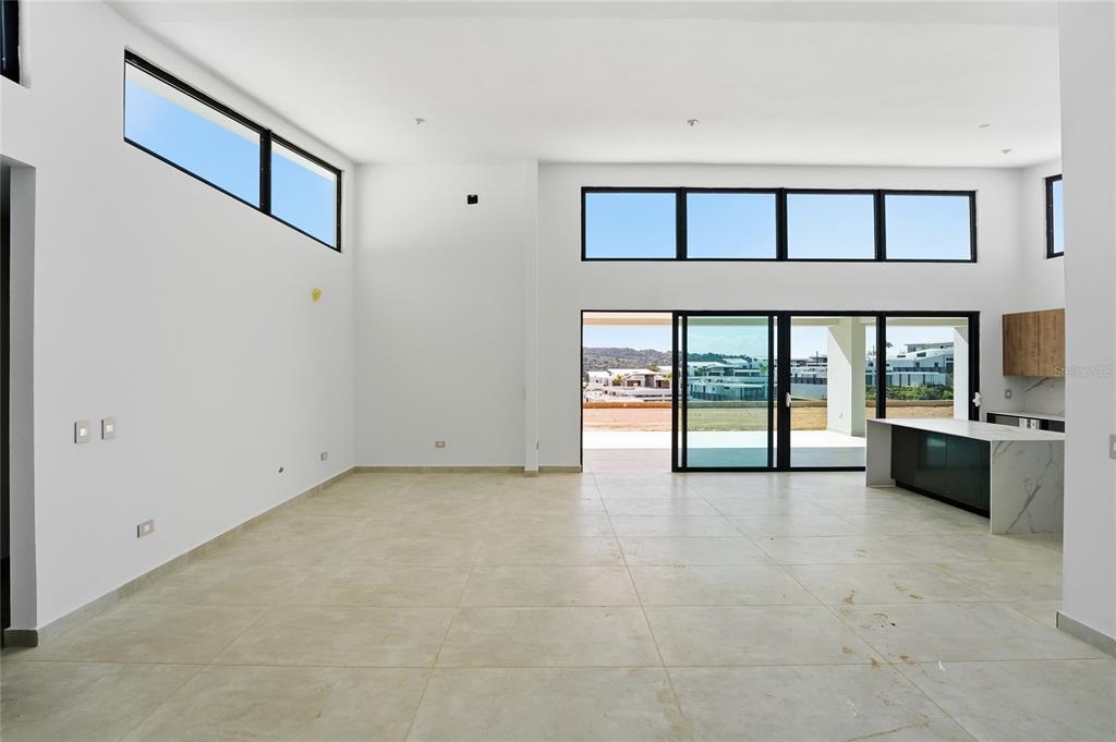 An open-concept living area with white walls, large windows, tile flooring, and a kitchen island — Monte azul MONTEAZUL, GUAYNABO, PR