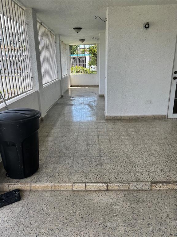 A covered patio features terrazzo flooring, white stucco walls, and metal security bars — Calle 18 BLOQUE 23, BAYAMON, PR