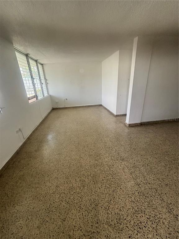 An empty room with white walls, a large window, and speckled terrazzo flooring — Calle 18 BLOQUE 23, BAYAMON, PR