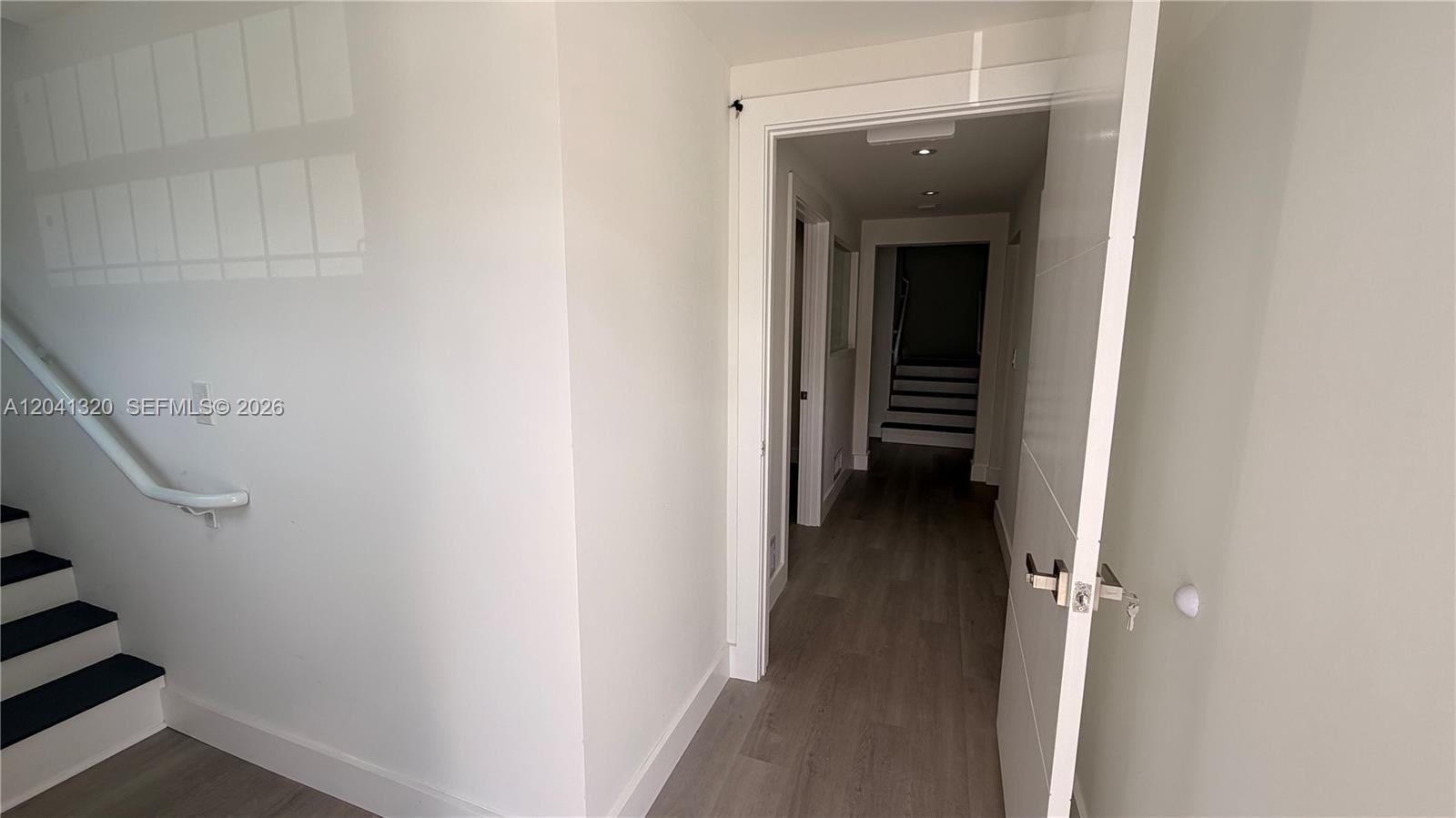 A white door opens into a hallway with wood-look flooring and a staircase — 8335 NW 64th St # 1, Medley FL 33166, MEDLEY, FL
