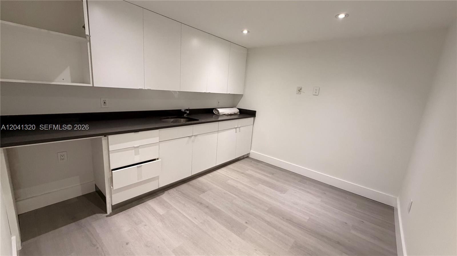 A kitchen area features white cabinets, a dark countertop, a sink, and light flooring — 8335 NW 64th St # 1, Medley FL 33166, MEDLEY, FL
