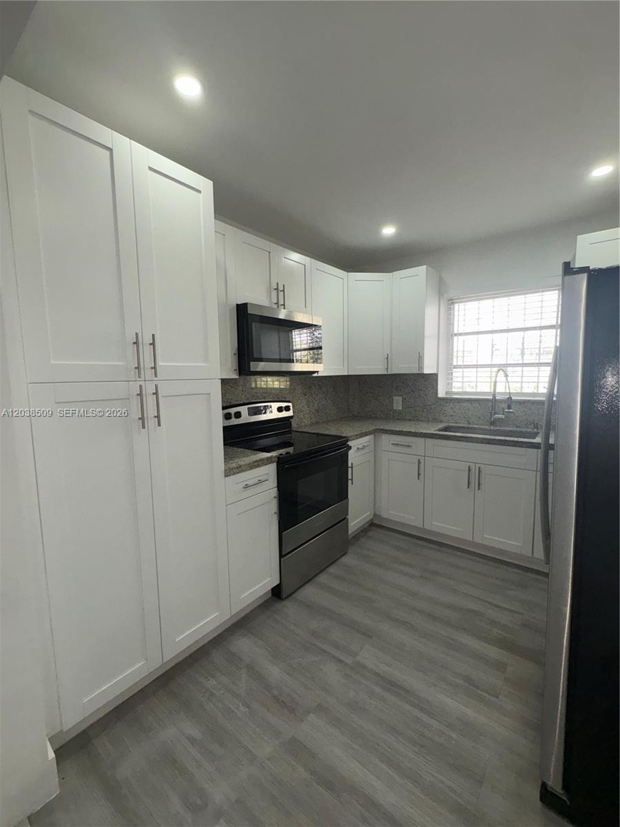 A kitchen features white cabinets, stainless steel appliances, and light-colored wood-look flooring — 2920 SW 15th St, Miami FL 33145, MIAMI, FL