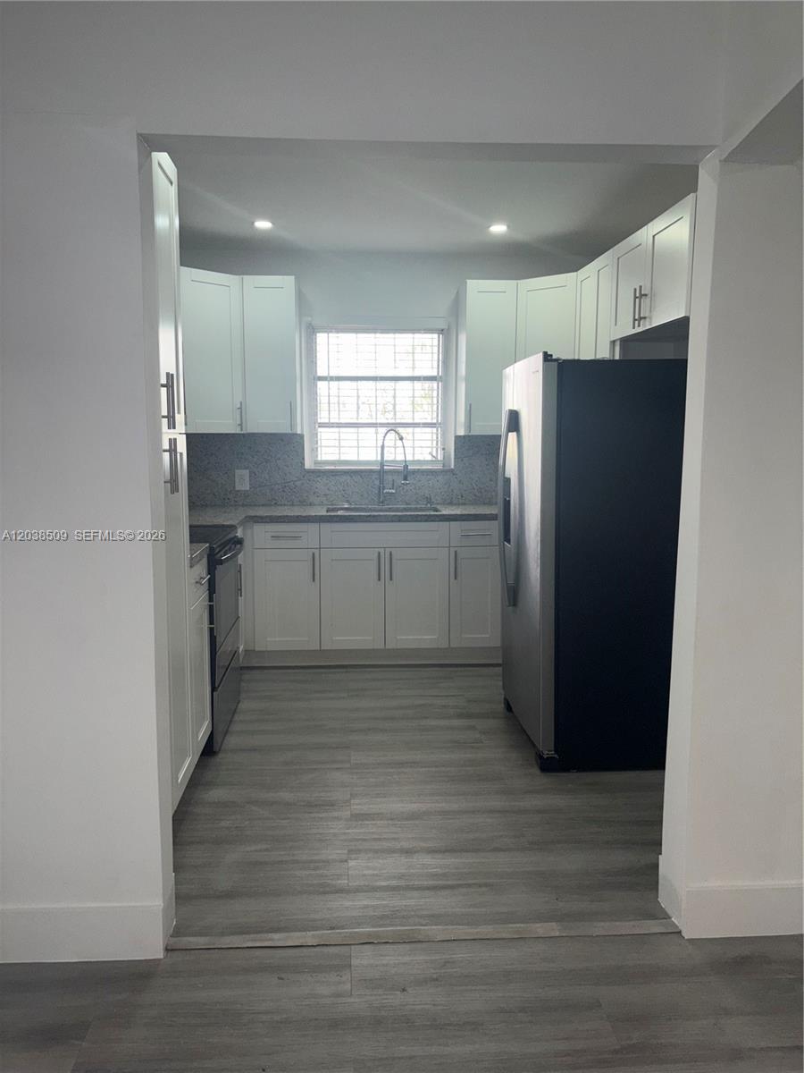 A kitchen features white cabinets, stainless steel appliances, granite countertops, and light wood-look flooring — 2920 SW 15th St, Miami FL 33145, MIAMI, FL